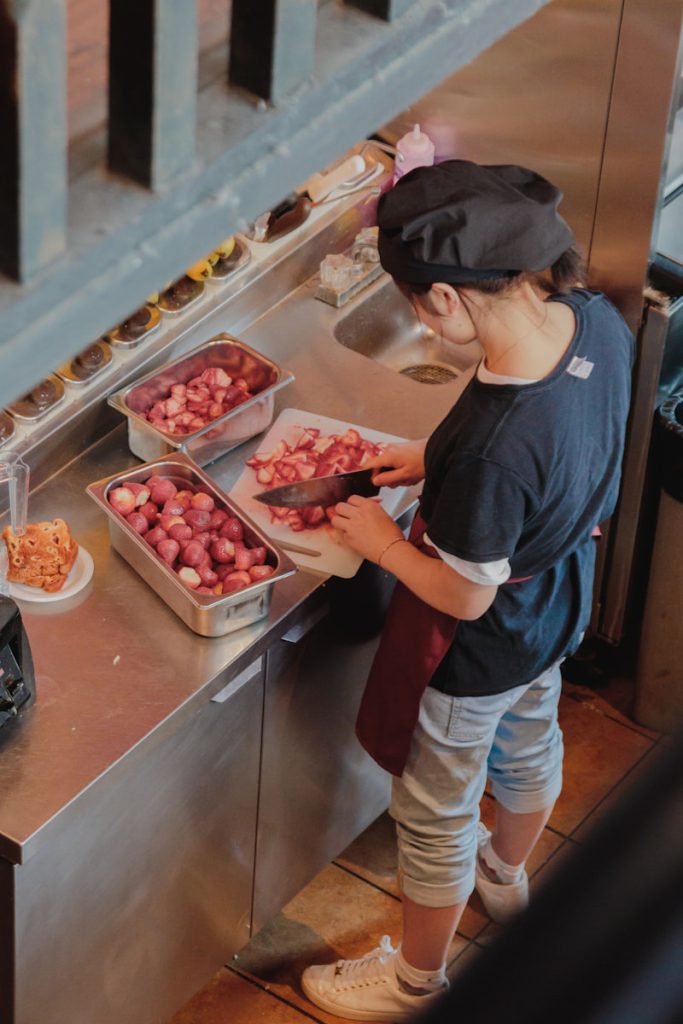 a woman standing in front of a kitchen counter filled with trays of food