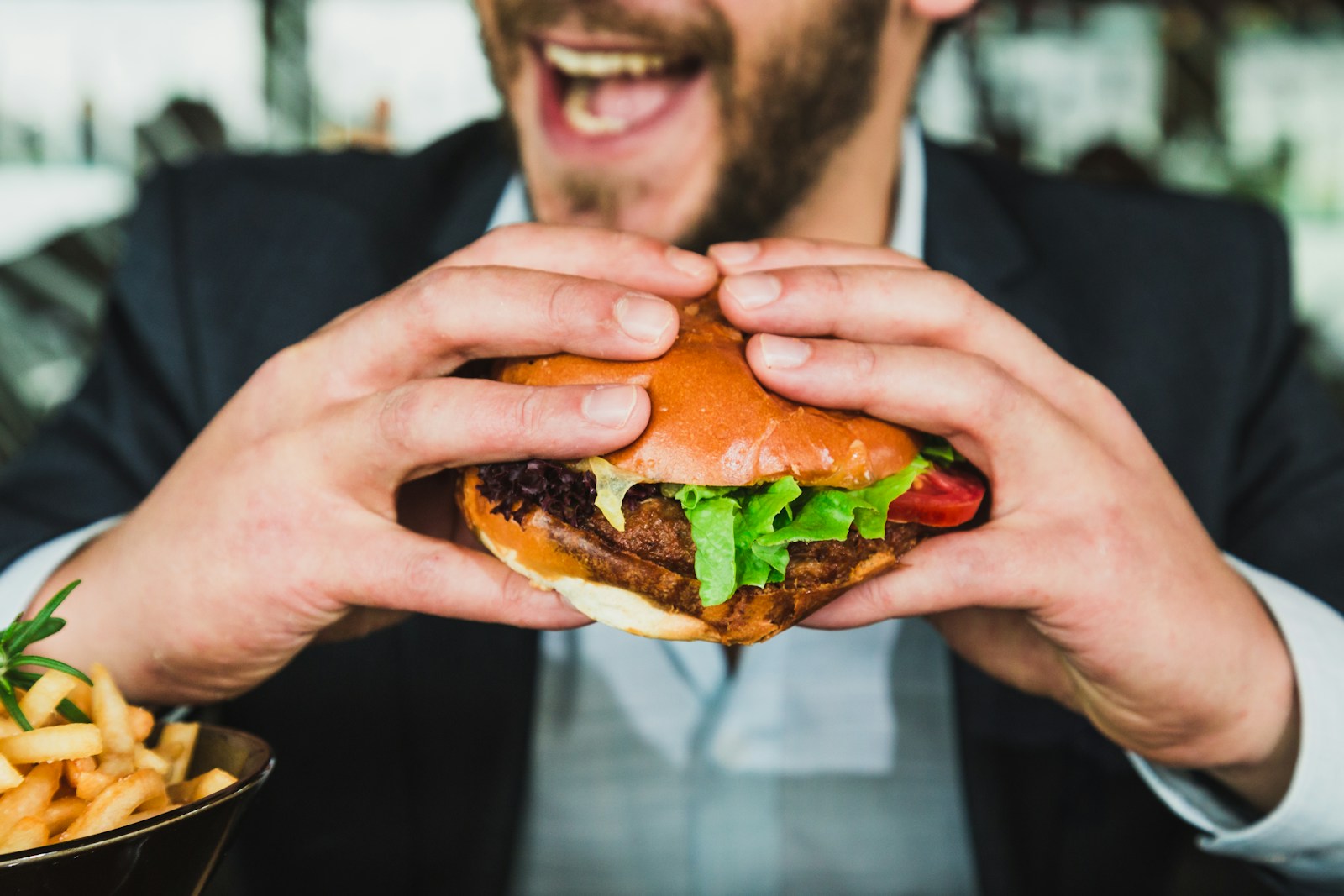 person holding burger bun with vegetables and meat for portion control